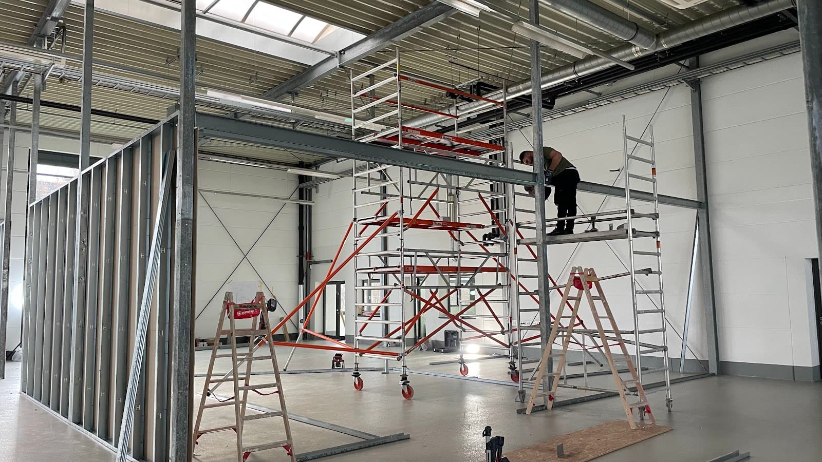 Ständerwerk und Rollgerüst beim Deckenausbau in einer Halle